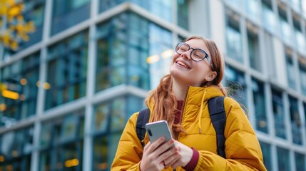 Wall Mural - Happy student using mobile phone in front of her university and looking away