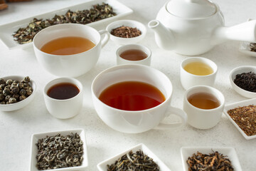 Wall Mural - A view of teacups, surrounded by assorted loose leaf tea and tea liquor.