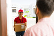 © AntonioDiaz - Delivery woman smiling and handing a package to a customer during a home delivery