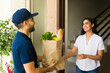 © AntonioDiaz - Attractive delivery guy handing a bag of groceries to a woman at her doorstep