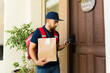 © AntonioDiaz - Delivery man holding a paper bag with takeout food and using a mobile app to confirm the delivery at the front door