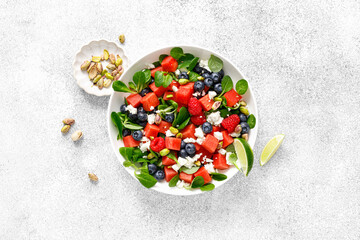 Wall Mural - Watermelon and feta cheese salad with blueberry, raspberry, pistachios and fresh greens, top view