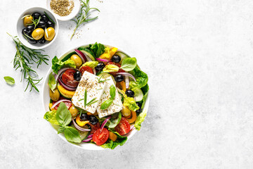 Wall Mural - Fresh healthy vegetable Mediterranean food salad of Greek feta cheese, tomato, olives, pepper, lettuce and green basil leaves, top view