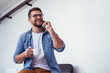 © kerkezz - Handsome bearded man leaning on office desk, drinking coffee and talking on the phone.