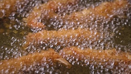 Sticker - breaded shrimps frying in hot oil, process of making tasty snack, food closeup, zoom in