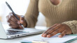 © Pompozzi - Close-up of Woman Writing Notes on Laptop