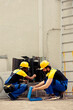 © DC Studio - Professional engineer using soft dusting brush to sweep away built up layer of dirt and debris from condenser coil while licensed serviceman refills cooling system refrigerant tank