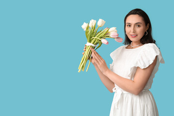 Wall Mural - Beautiful young woman with bouquet of tulips on blue background. International Women's Day