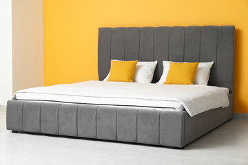 Sticker - New orthopedic mattress with blanket on stylish bed near yellow wall in room