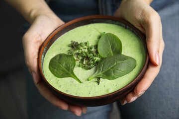 Wall Mural - Woman holding bowl of delicious spinach cream soup, closeup