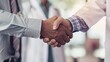 © admin_design - Closeup of two doctors shaking hands, demonstrating trust and collaboration in a medical setting.