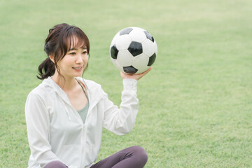 Wall Mural - 運動場でサッカーボールを持つサッカーファン・サポーターの日本人女性
