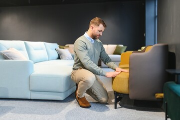 Canvas Print - A handsome young man chooses furniture in a store