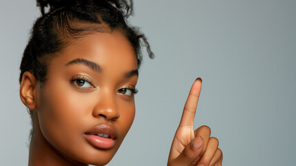 Close-up of a beautiful woman's face Raise your hand with your index finger. gray background