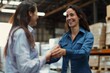 © alisaaa - Businesswoman handshaking with a client while working at a distribution warehouse