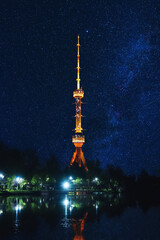 Wall Mural - illuminated TV tower at night in Tashkent in Uzbekistan with a reflection in water of a river under blue sky with stars