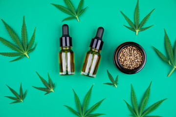 Flat lay composition of marijuana and hemp seeds on green color paper background