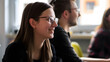 © Gita - A group of students smiling and engaging in a classroom environment. The focus is on a young woman wearing glasses in the foreground with classmates in the background.