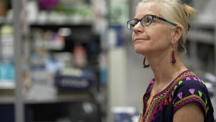 Wall Mural - Extreme closeup of mature woman wearing ethnic top, walking through big box hardware store looking for products for home renovation redecorating project.