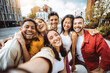 © Davide Angelini - Multiracial group of friends taking selfie pic with smart mobile phone device - Happy young people having fun walking in city street - Technology and people life style concept
