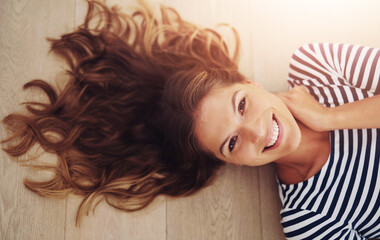 Poster - Portrait, home and woman on wooden floor, smile and relax with weekend break, playful and calm. Face, top view and girl on ground, peaceful and silly in living room, comfortable and carefree in house