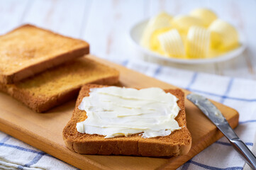 Wall Mural - spread butter on a golden crispy pieces of toast on a cutting board, selective focus.