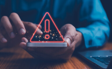 Businessman or it staffs, programmer, developer using Smartphone with triangle caution warning sign for notification error and maintenance concept. Virus detected warning, Cybercrime protection
