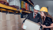 © totojang1977 - Engineer woman and businessman wearing a hardhat standing cargo at goods warehouse and check for control loading from Cargo freight ship for import and export by report on laptop. Teamwork concept