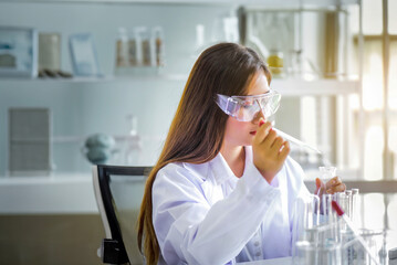 Wall Mural - Attractive young Asian scientist woman lab technician assistant analyzing sample in test tube at laboratory. Medical, pharmaceutical and scientific research and development concept	