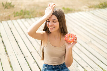 Wall Mural - Teenager girl holding a donut at outdoors has realized something and intending the solution