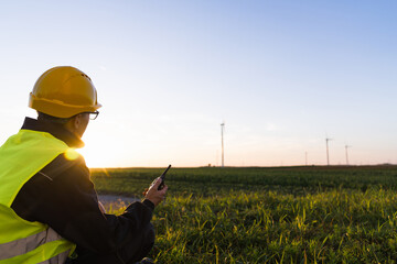 Aufkleber - Worker with digital tablet sits on the grass and looks at wind turbines