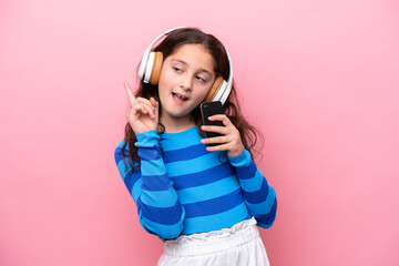 Wall Mural - Little girl isolated on pink background listening music with a mobile and singing