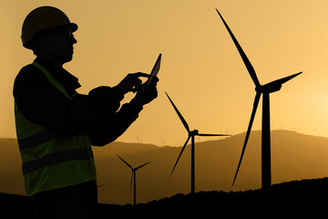 Aufkleber - Engineer with digital tablet works on a field of wind turbines at sunset	