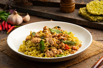 Wall Mural - Spicy stir fried instant vegetable noodle or japanese style Jade noodles with minced pork and thai basil leaves in white plate.Healthy thai style food.