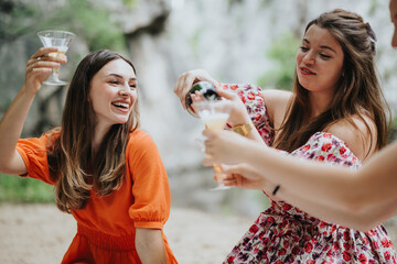 Wall Mural - Vibrant scene of young women at an outdoor picnic, smiling and drinking champagne. They are joyfully toasting and enjoying the moment together.