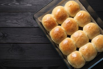 Wall Mural - Delicious dough balls in baking dish on black wooden table, top view. Space for text