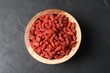© New Africa - Dried goji berries in bowl on dark textured table, top view