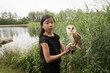 © Milou Dirks - portrait of young asian girl holding barn owl on glove in nature near lake