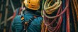 © pitu - A focused construction worker wearing a safety harness and helmet prepares for an ascent on site. Construction Worker Ascending