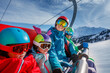 © Sergey Novikov - Smiling family on ski lift, snowy mountains in the background