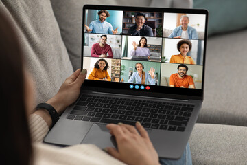 Poster - A woman sits on a couch and uses a laptop to participate in a virtual meeting. The laptop screen displays nine individual video feeds of the other participants.