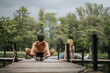 © qunica.com - Young adults performing stretching exercises on a wooden pier surrounded by nature, promoting fitness, wellness, and outdoor activities.