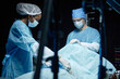 © Seventyfour - Two surgeons in full protective clothing preparing patient for surgery in operating room with machines and equipment copy space