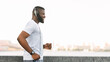 © Prostock-studio - A man wearing headphones runs along a waterfront in a city.