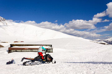 An extreme man actively rides a snow motorcycle in the deep snow of a mountain slope in winter. Gudauri, Georgia