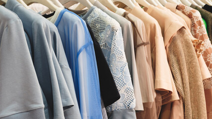 Poster - A row of clothes hanging on a rack, including a blue shirt with a white flower design. The clothes are neatly arranged and appear to be for sale