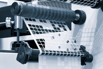 Poster - A roll of white paper is passed through the machine. printer and sticker machine, which is used for printing and applying stickers to packaging industrial products. Concept of precision efficiency