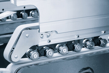 Poster - Part of a modern roller conveyor with metal and plastic rollers for the production of various products, industrial concept background.