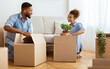 © Prostock-studio - Moving Apartment. Happy Black Spouses Packing Stuff In Cardboard Boxes Sitting On Floor Indoor. Selective Focus