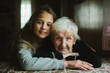 © De Visu - A heartwarming portrait of an elderly lady with her young granddaughter in their cozy home.